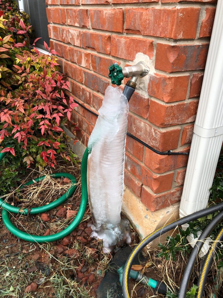 outdoor faucet and hose covered in thick ice