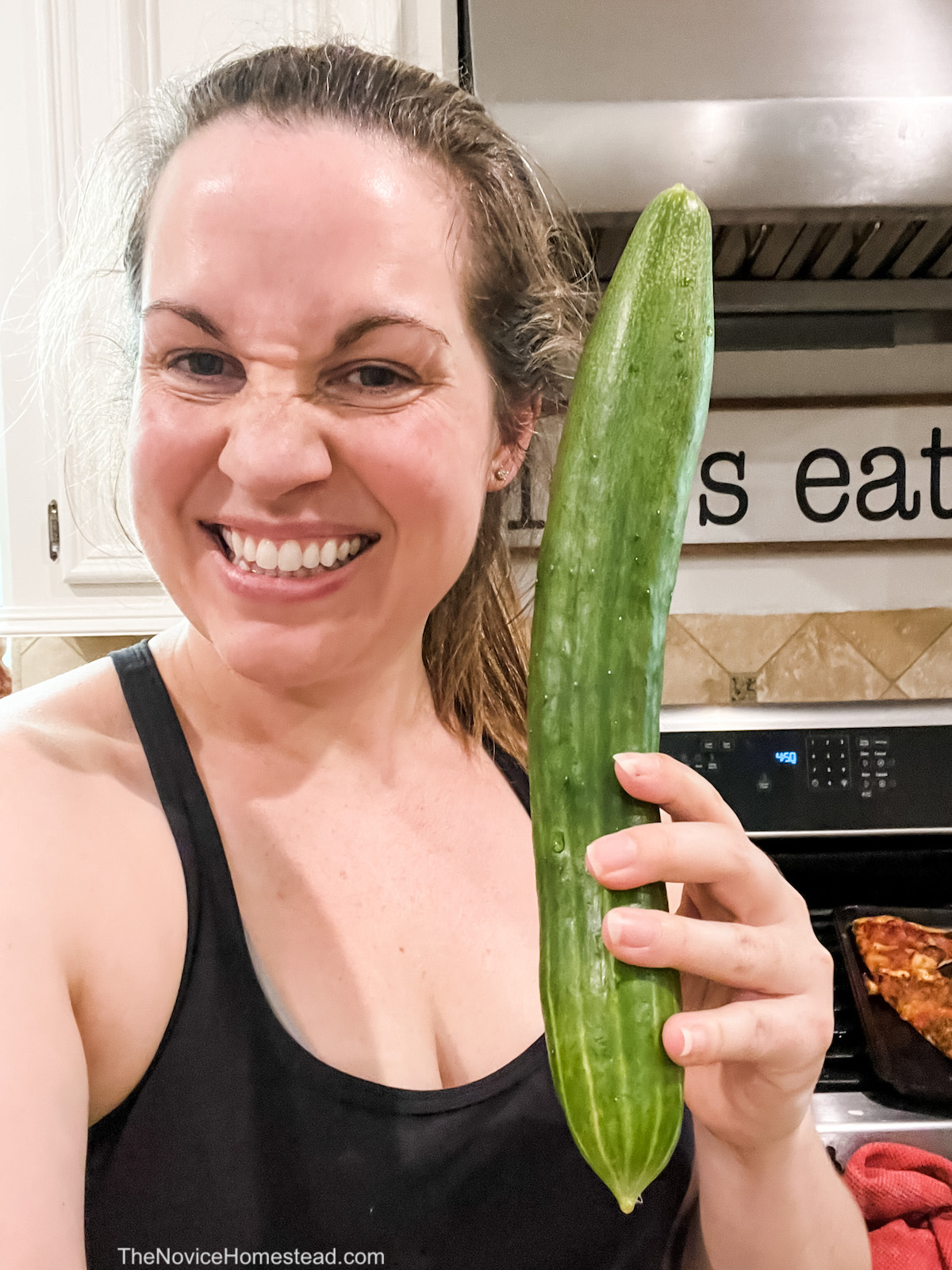 woman holding up a large cucumber